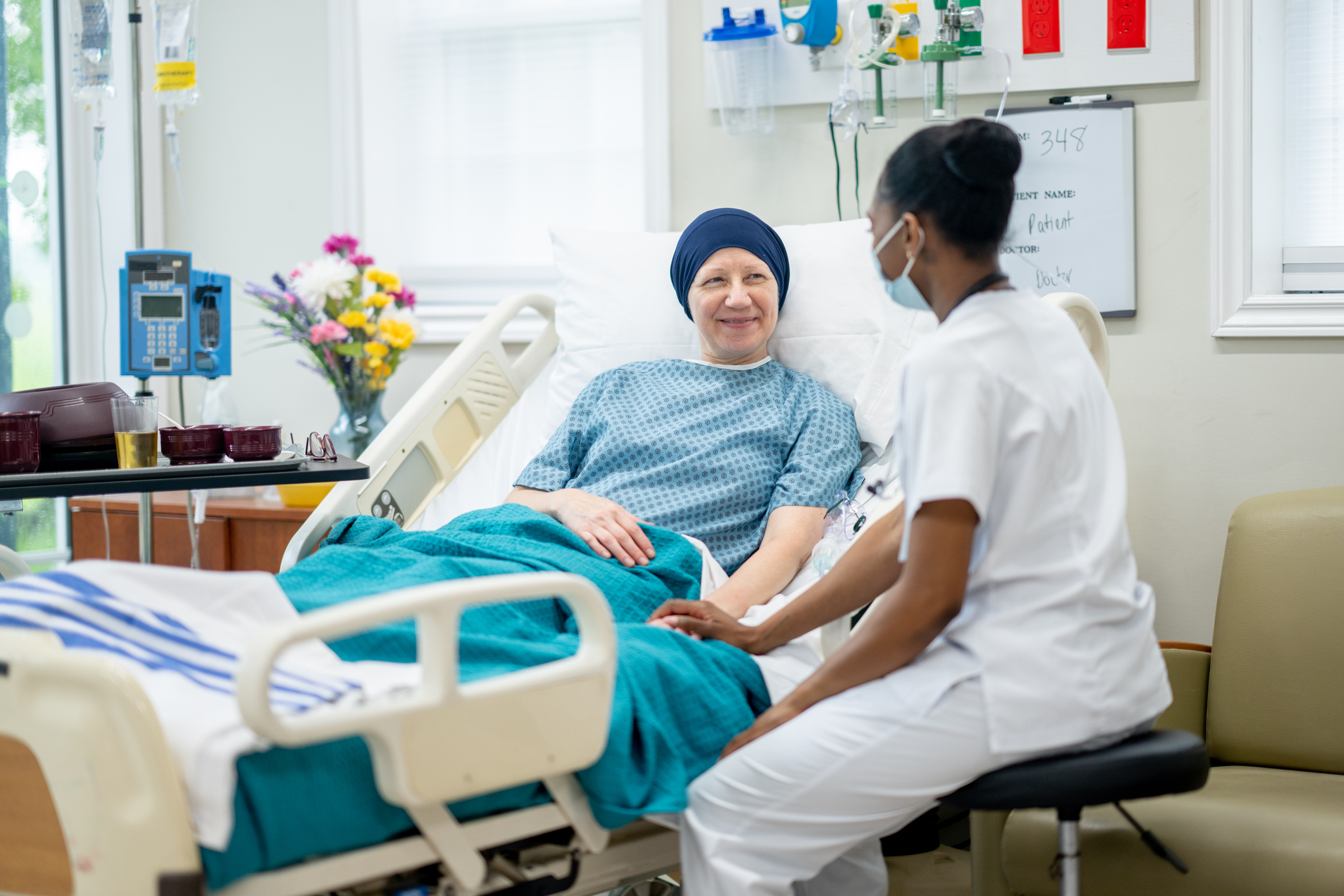 Femme cancéreuse sur lit d'hôpital pendant que l'infirmier lui tient la main